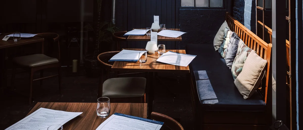 Loxleys courtyard seating, dark walls, warm light and set tables.