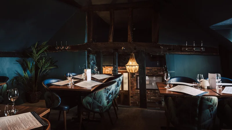 Loxleys dining room, warm low light with exposed beams and a chandelier.