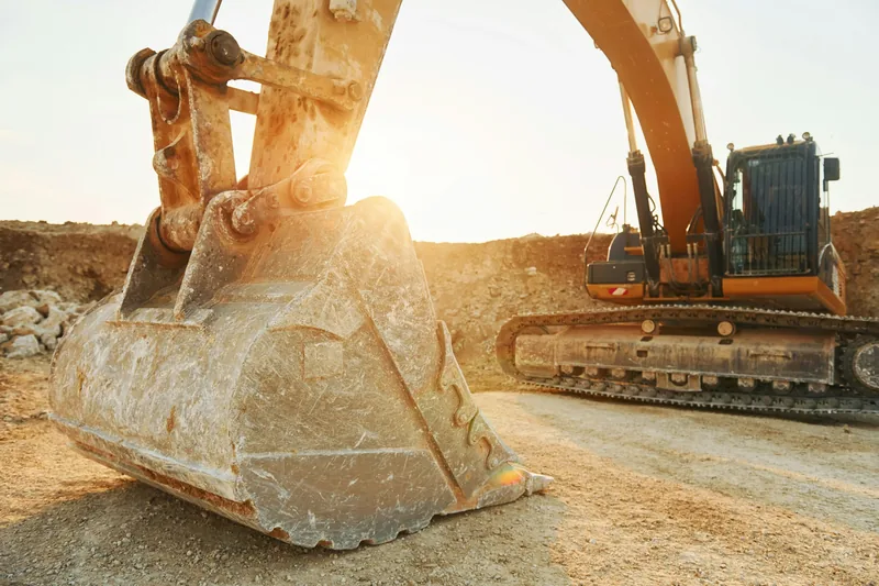 PlantFix UK: a tracked excavator on a work site at sunset.