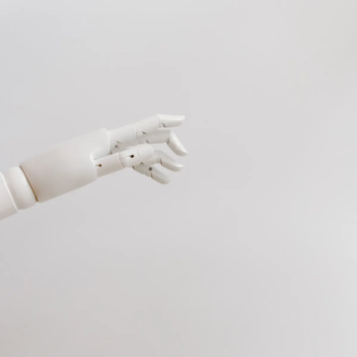 A white robotic hand reaching in from the left of an otherwise empty pale grey frame.